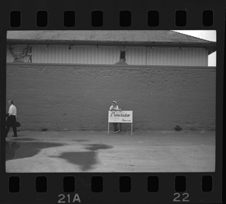 Man leaning on sign near entrance gates to Bob-Lo ferry