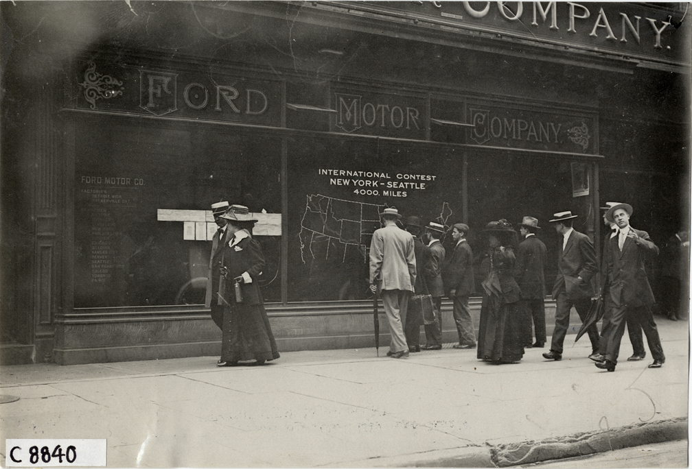 Men and women standing in front of Ford Motor Company dealership