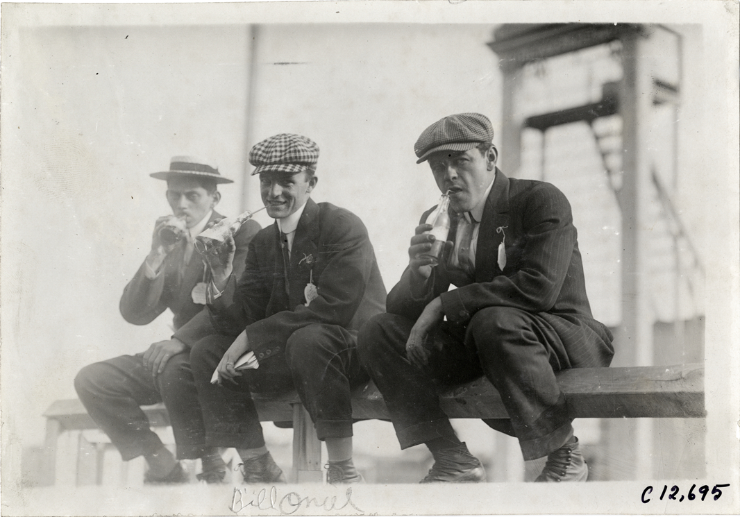 Three men drinking from bottles, 1910 Empire City races