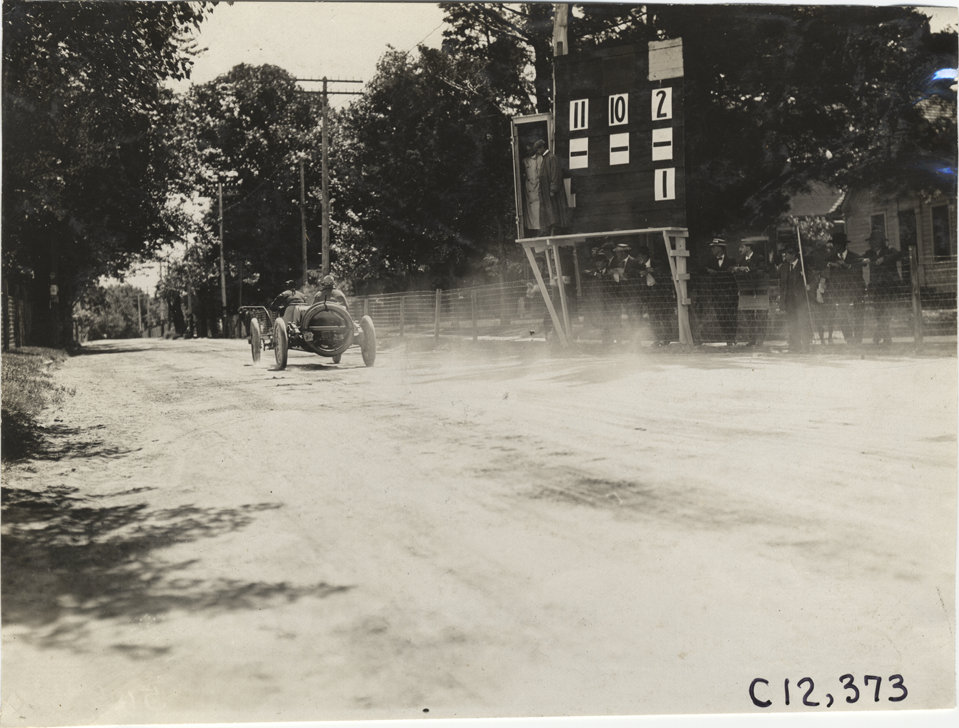 Racecar passing scoreboard, 1909 Crown Point races