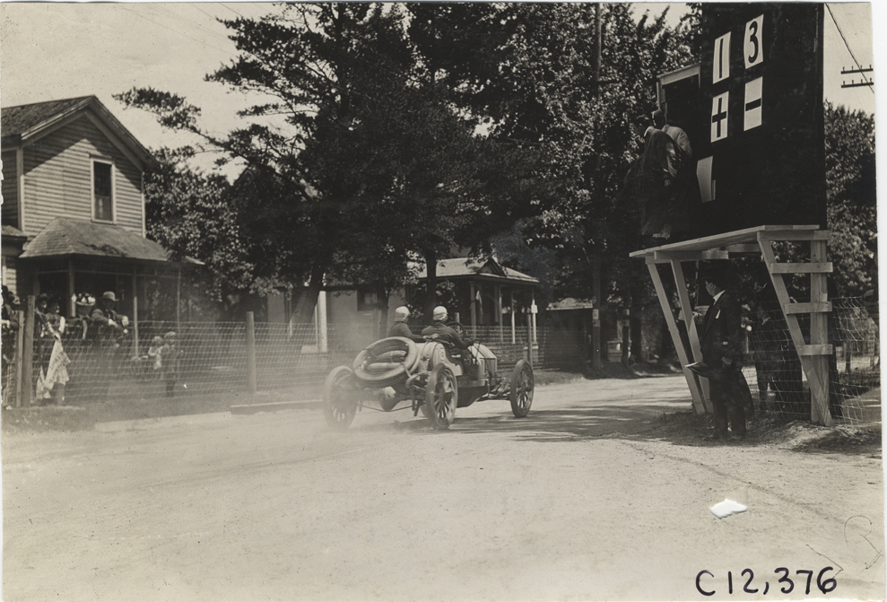Racecar passing scoreboard, 1909 Crown Point races