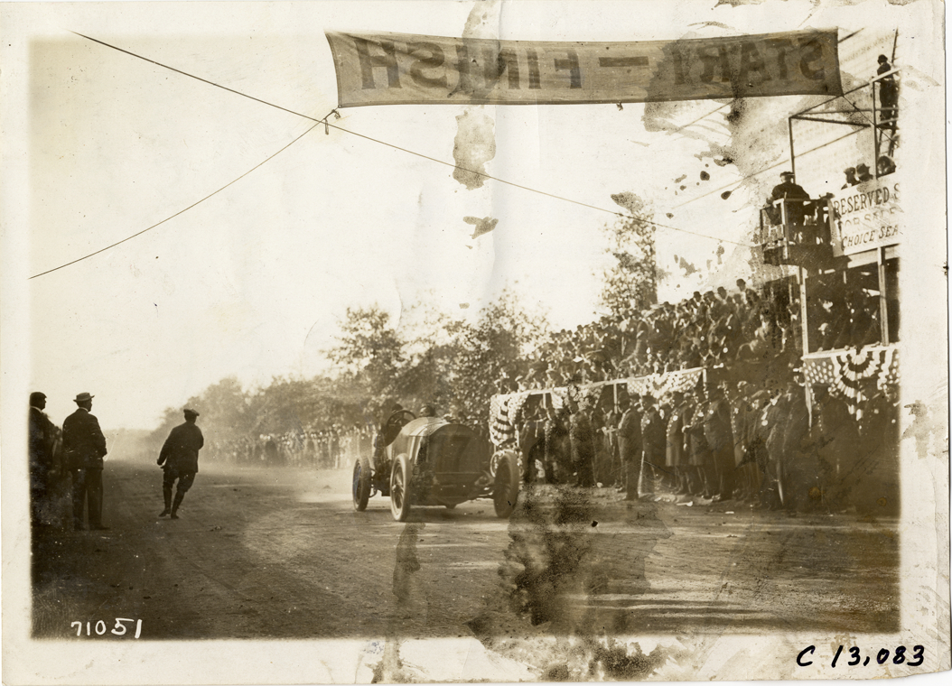 Spencer Wishart crossing finish line in Mercedes racecar, 1911 Fairmount Park races