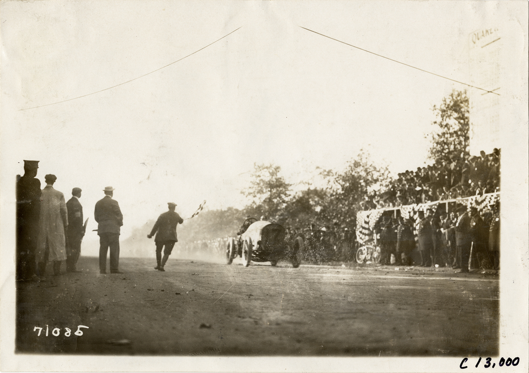 Spencer Wishart crossing finish line in Mercedes racecar, 1911 Fairmount Park races