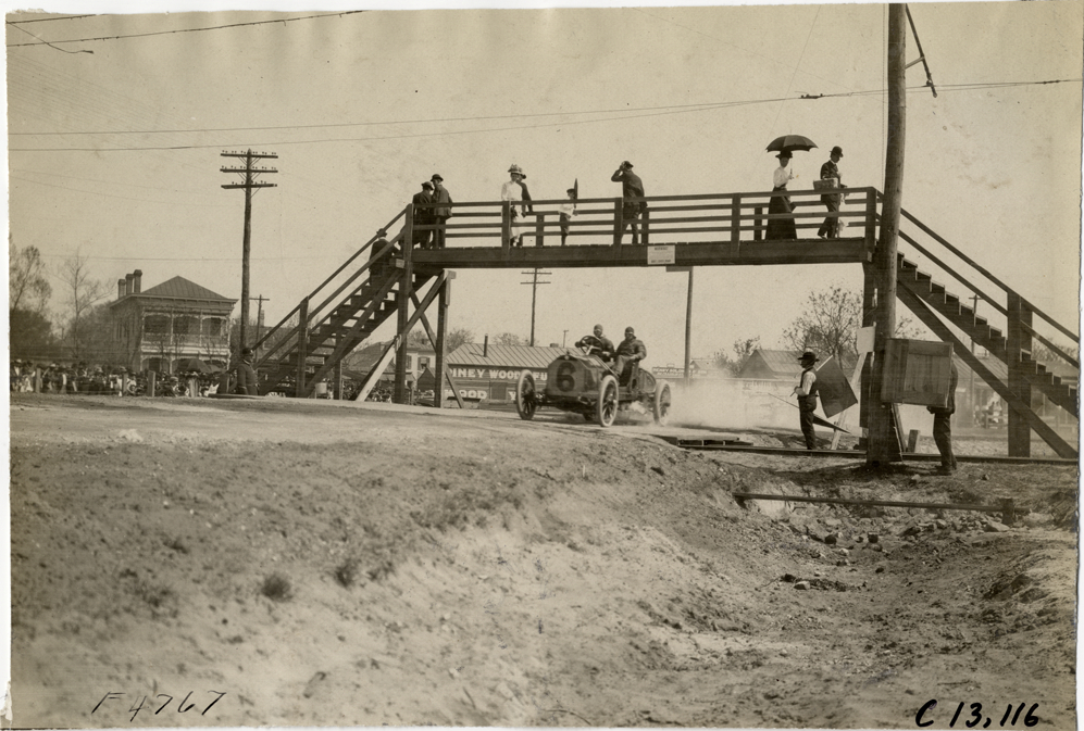 Racecar passing under pedestrian bridge, 1908 Grand Prize races