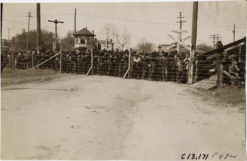 Spectators standing behind fence, 1908 Grand Prize races