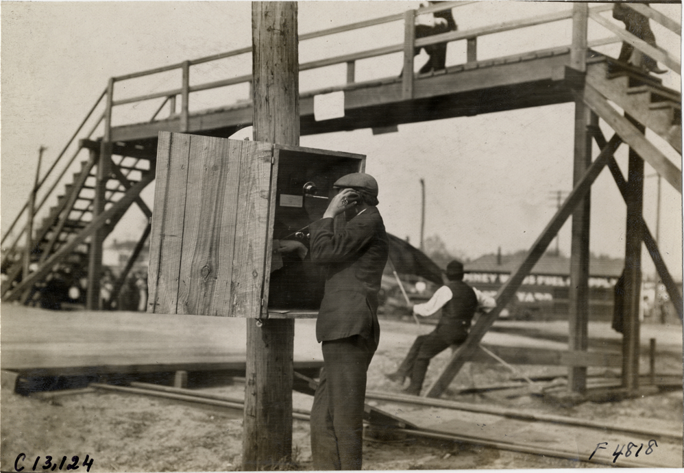 Man making telephone call, 1908 Grand Prize races