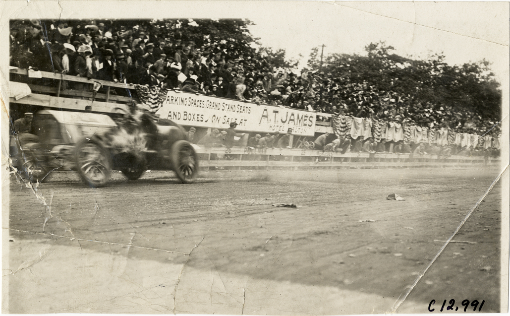 Racecar passing spectators in bleachers, 1910 Fairmount Park races