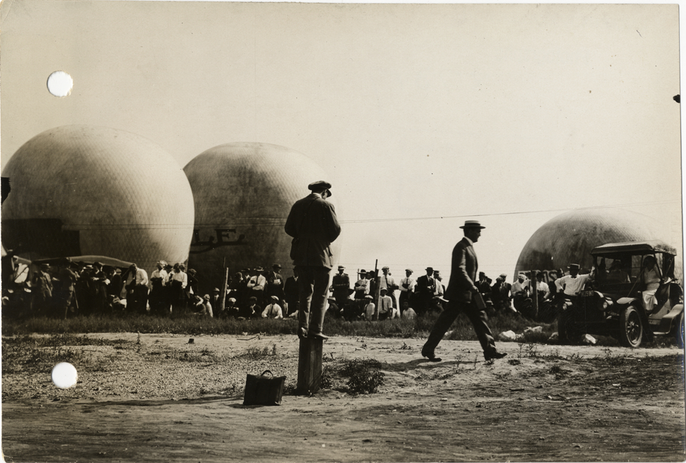 Man photographing hot air balloons, 1913 Indianapolis 500 automobile race