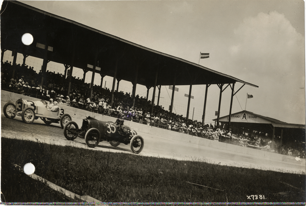 Stutz and Mason cars racing past grandstand, 1913 Indianapolis 500 automobile race