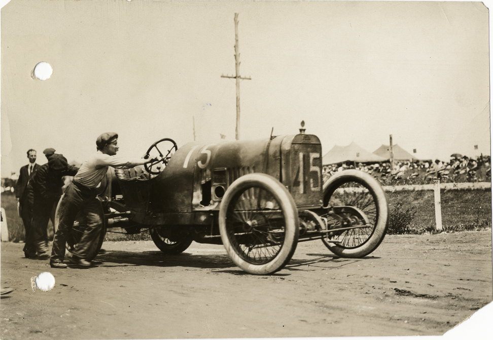 Paul Zuccarelli pushing Peugeot racecar to the barns, 1913 Indianapolis 500 automobile race