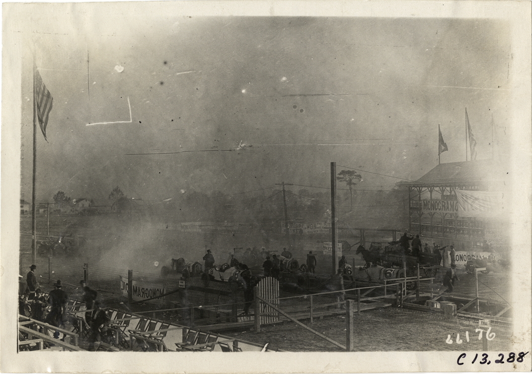 Racecars inside fenced enclosures, 1910 Grand Prize races