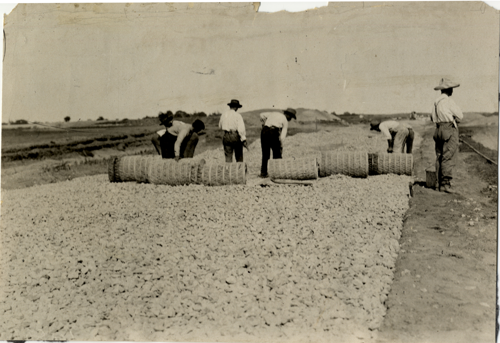 Men laying steel mesh on gravel road, 1908 Vanderbilt Cup races