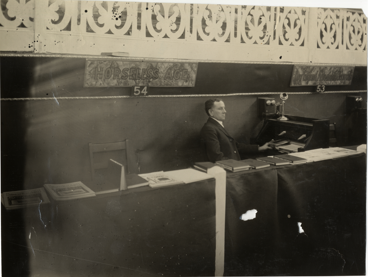 Man in booth for "Horseless Age" magazine, 1909 Boston Auto Show