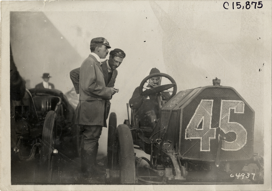 Officials standing next to racecar, 1910 Vanderbilt Cup races