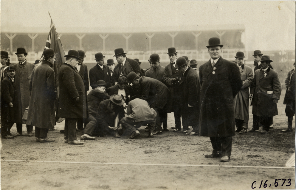 Officials with runner Tom Longboat on side of track