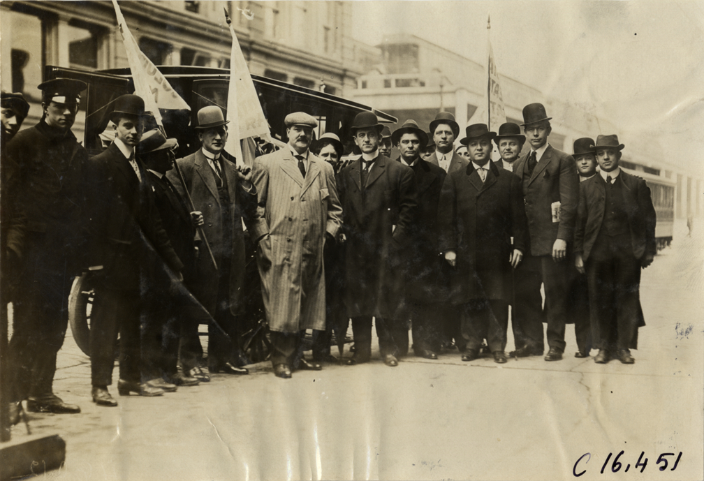 Men posing in front of automobile