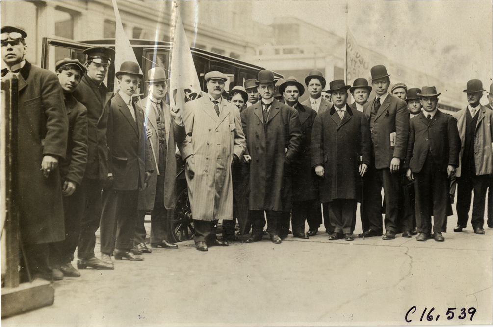 Men posing in front of automobile