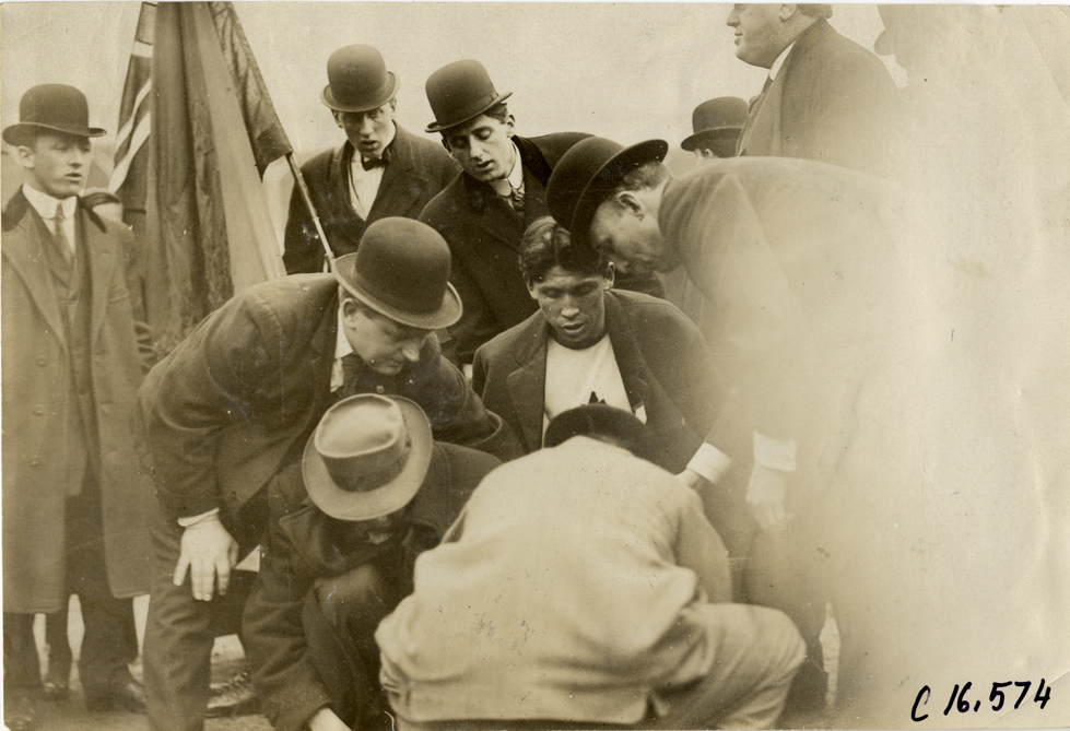 Officials with runner Tom Longboat on side of track