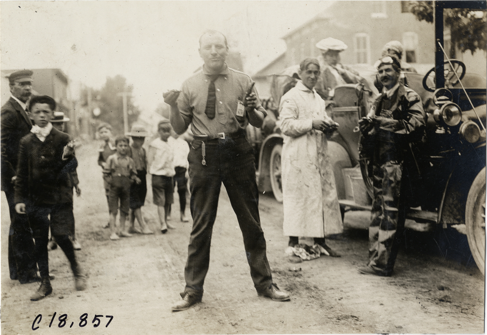 Official standing in street, 1906 Glidden Tour