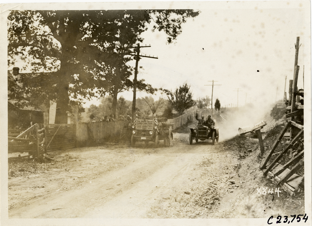Motorists in automobile passing Rapid truck on roadside, 1910 Glidden Tour