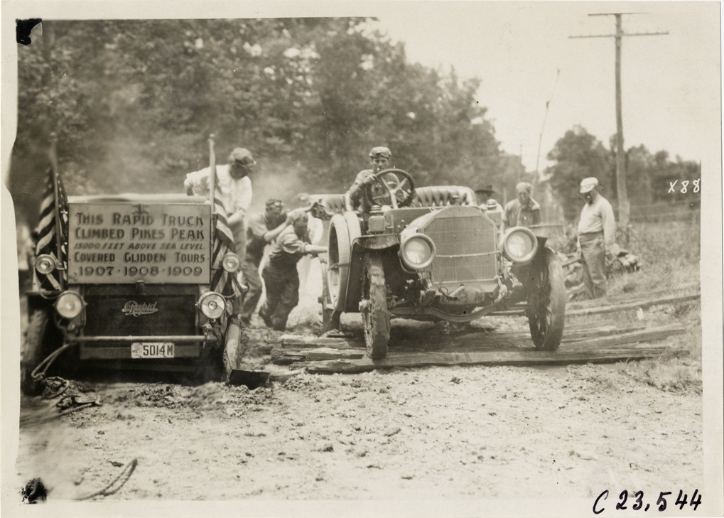 Motorist driving automobile over boards on muddy road, 1910 Glidden Tour