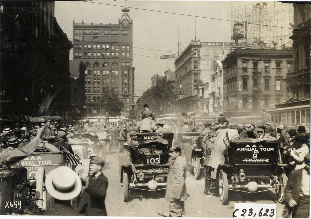 Automobiles, motorists and spectators in street, 1910 Glidden Tour