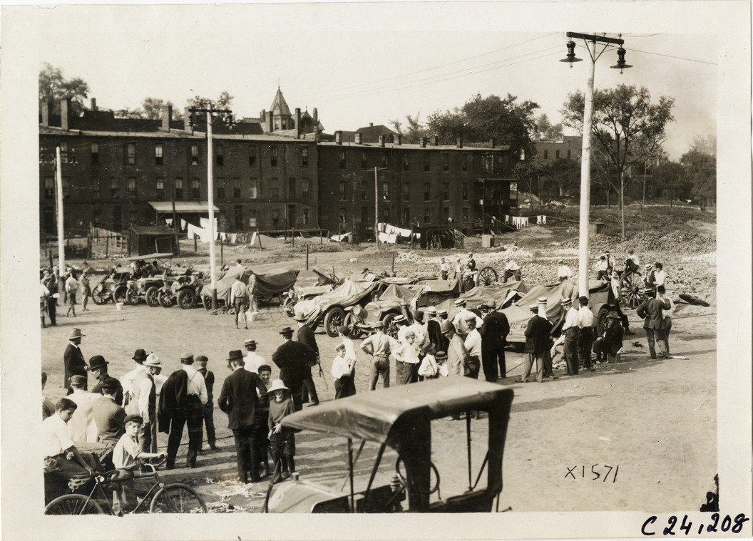 Spectators looking at automobiles in vacant lot, 1910 Glidden Tour