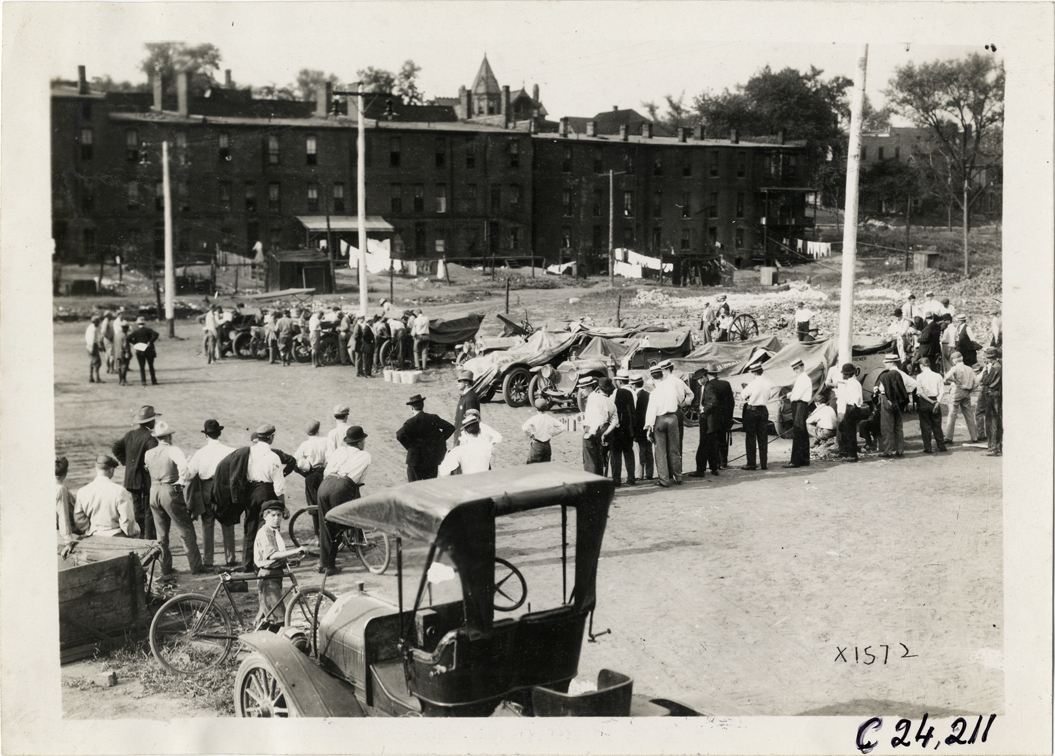 Spectators looking at automobiles in vacant lot, 1910 Glidden Tour