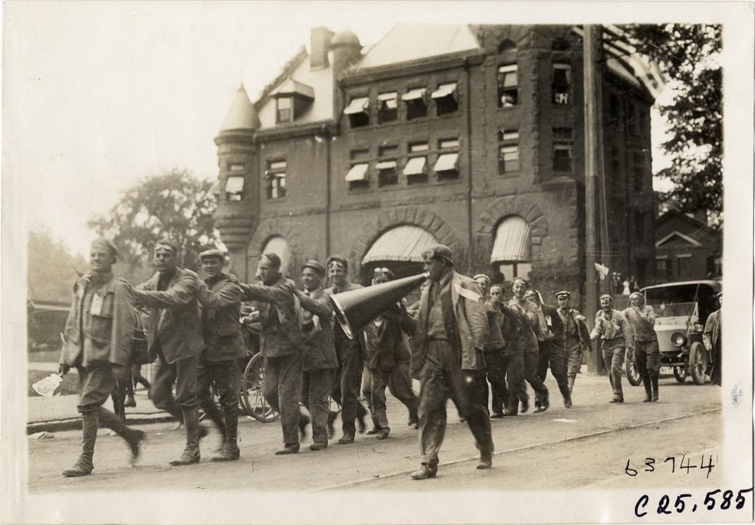 Official with megaphone leading group of motorists in queue, 1910 Munsey Historic Tour