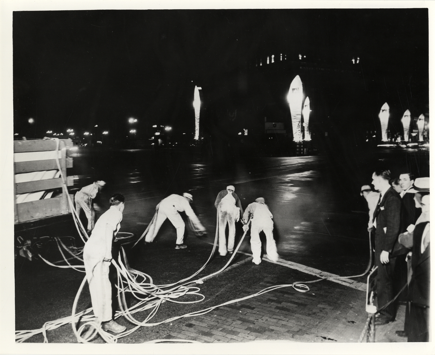 Workers spraying gold paint on Woodward Avenue, Detroit Automotive Golden Jubilee Celebration