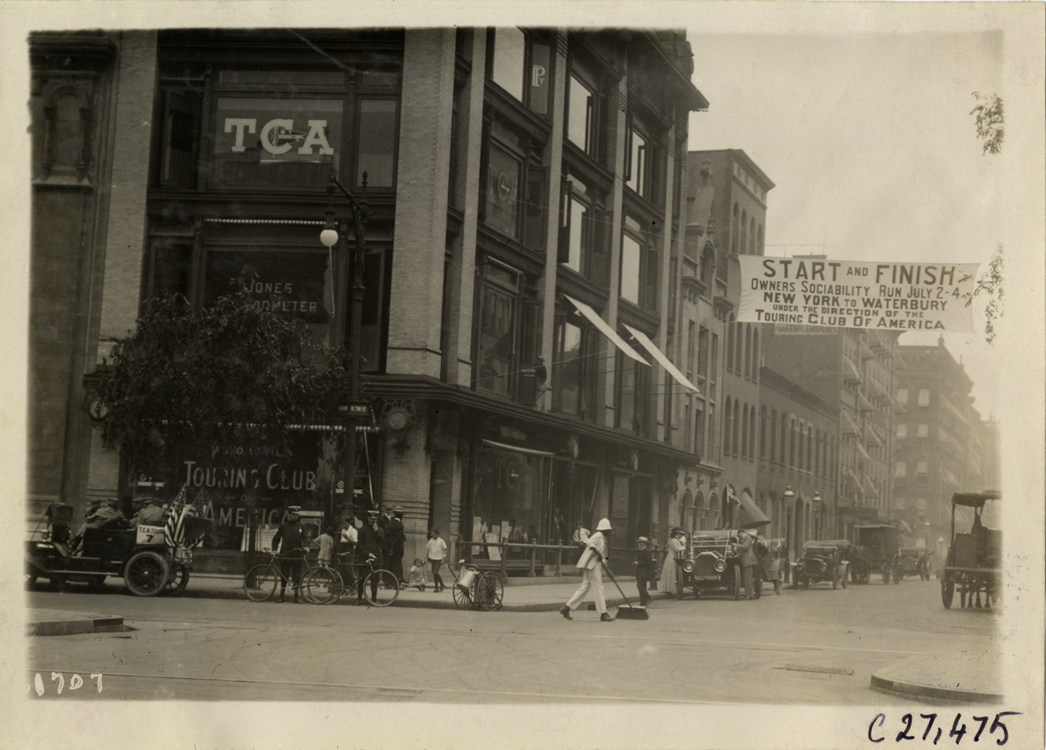 Banner suspended over street next to T.C.A. office, 1910 Touring Club of America Owners' Sociability Run