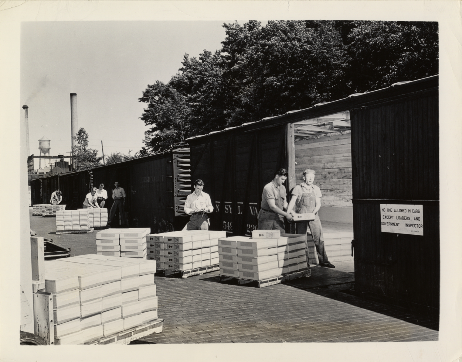 Workers loading 75 mm. and 105 mm. shells onto railroad freight cars