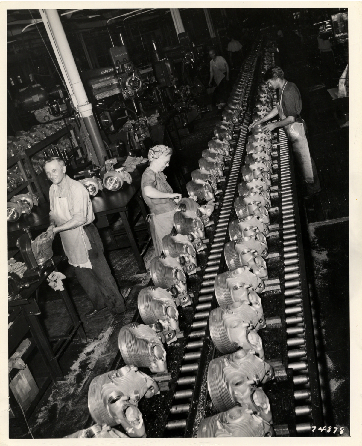 Men and women workers assembling Pratt & Whitney engine cylinder heads