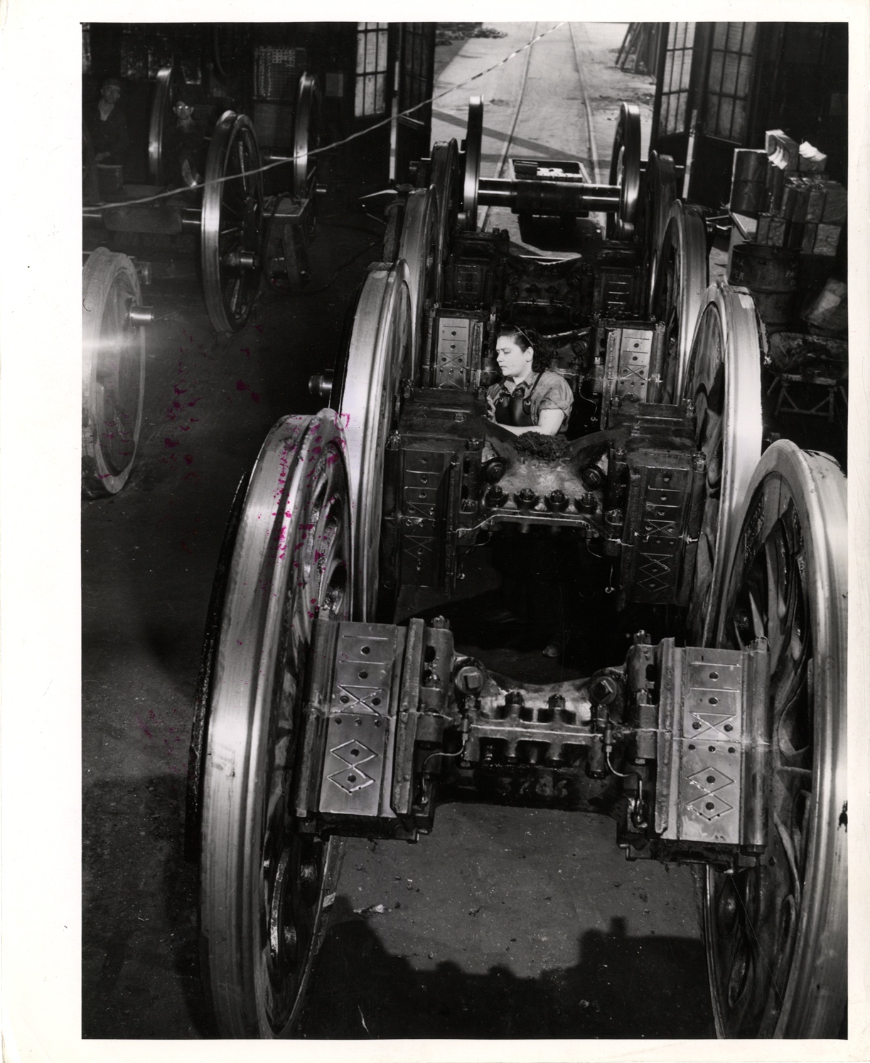Carmen Honesto cleaning railroad engine driver wheels, Atchison, Topeka and Sante Fe Railroad