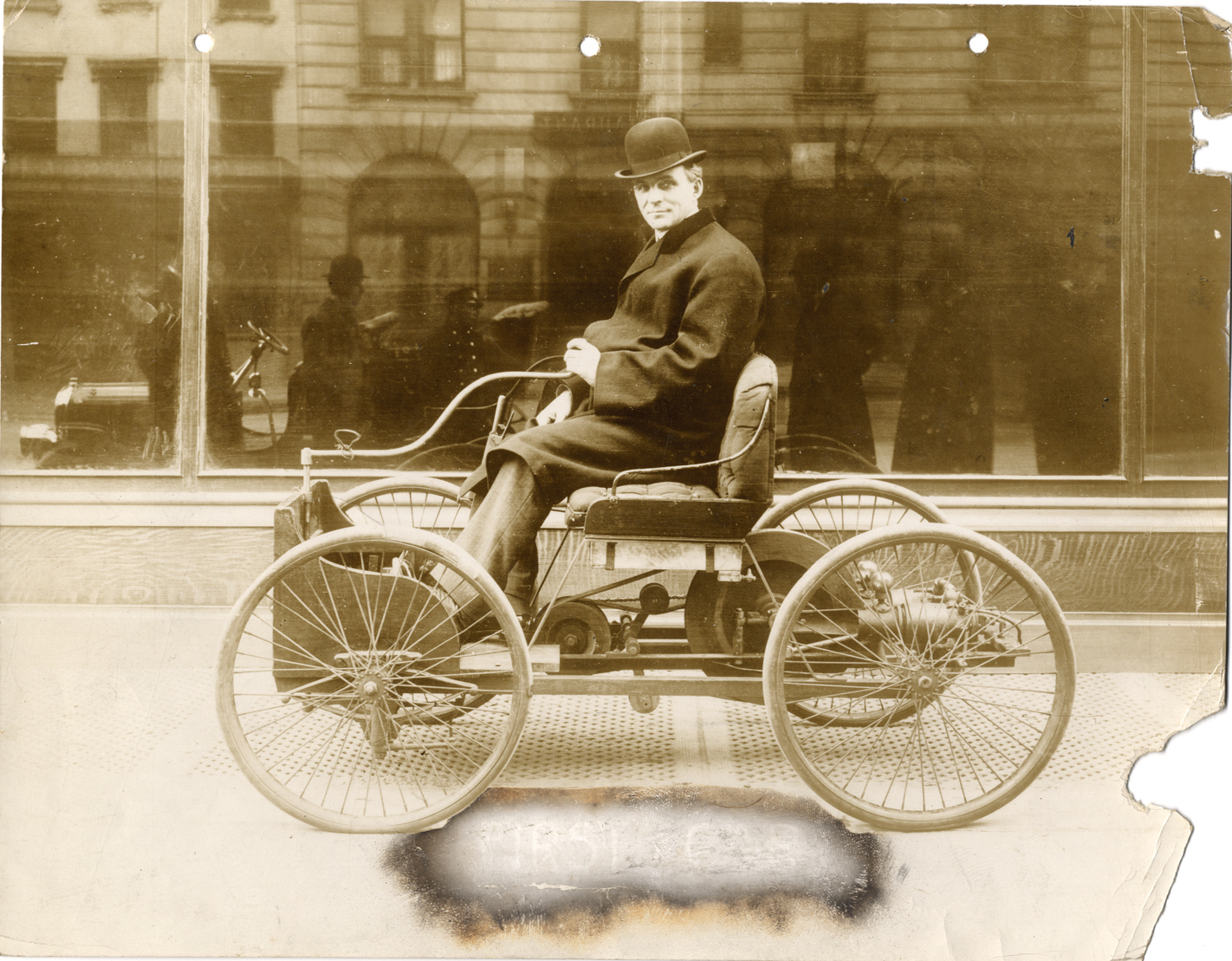 Henry Ford posing in 1896 Ford quadricycle