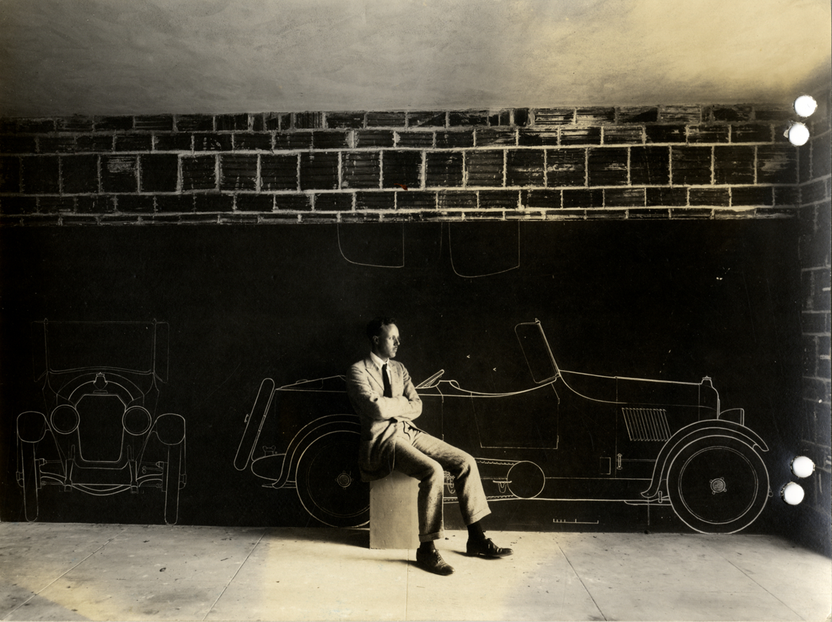 James Scripps Booth posing with drawing of Da Vinci "Pup" cyclecar