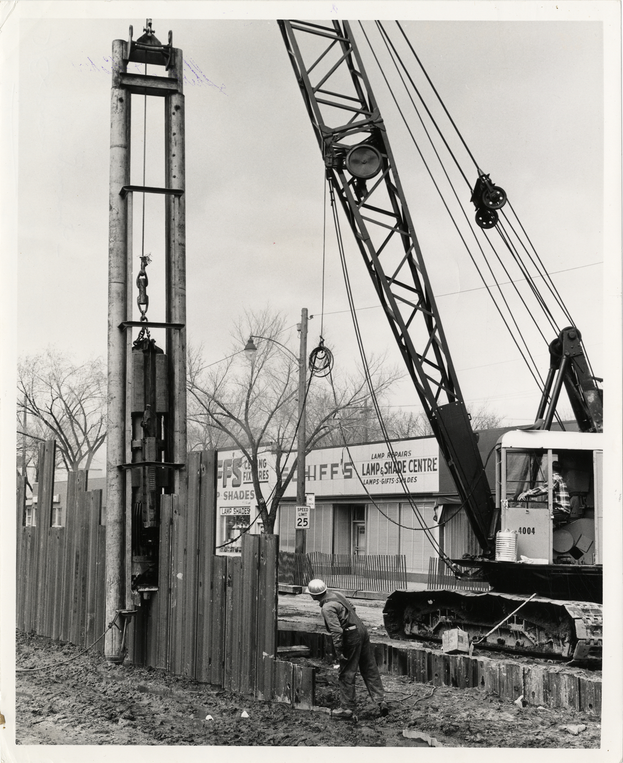 Workers operating pile driver during construction of John C. Lodge Expressway