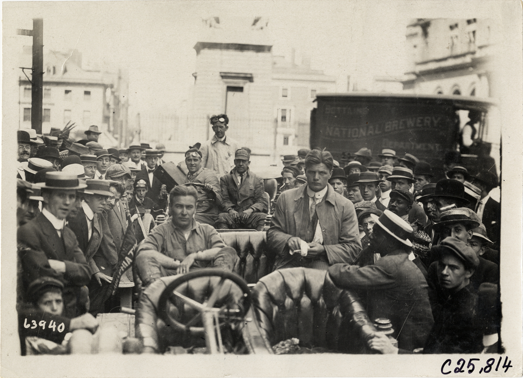 Spectators surrounding motorists in automobile, 1910 Munsey Historic Tour