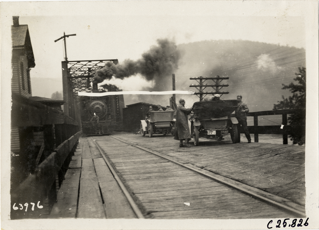 Automobiles and locomotive on railroad bridge, 1910 Munsey Historic Tour