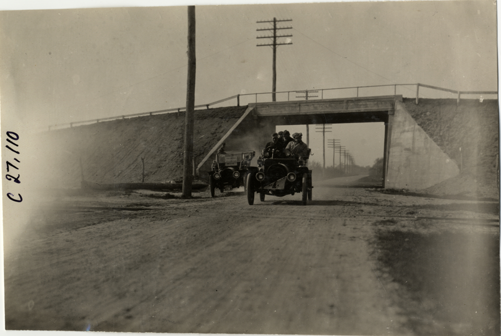 Motorists in automobile traveling under railroad bridge, 1909 New York Economy Contest