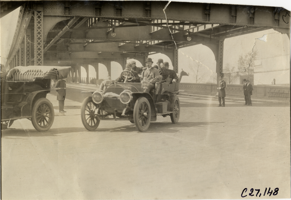 Motorists in automobile passing under bridge, 1909 New York Economy Contest