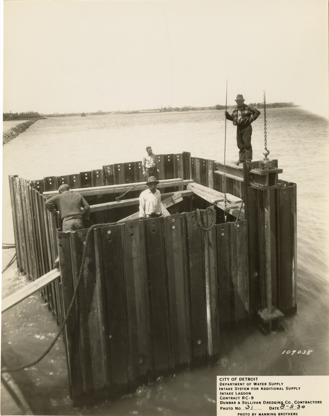 Workers posing on steel sheet piling cell, intake lagoon, Detroit water supply system