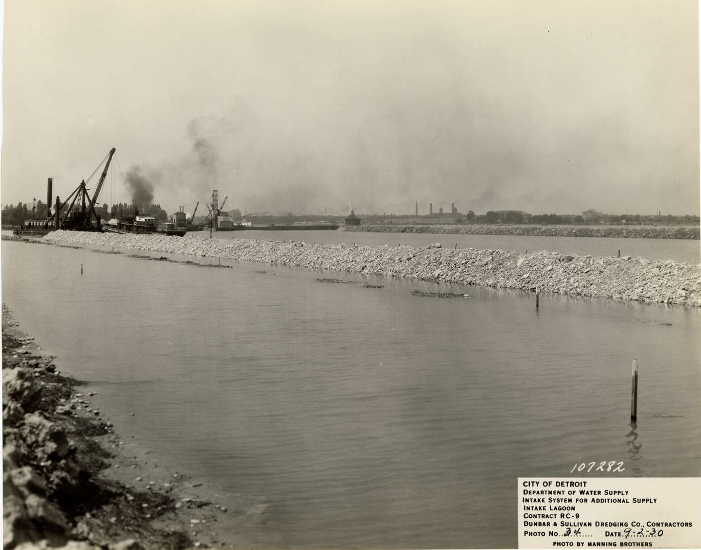 Crane depositing rock on dike, intake lagoon, Detroit water supply system