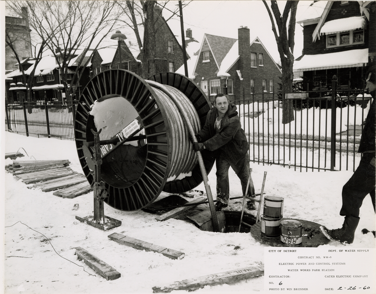 Worker feeding cable into manhole, Waterworks Park, Detroit water supply system