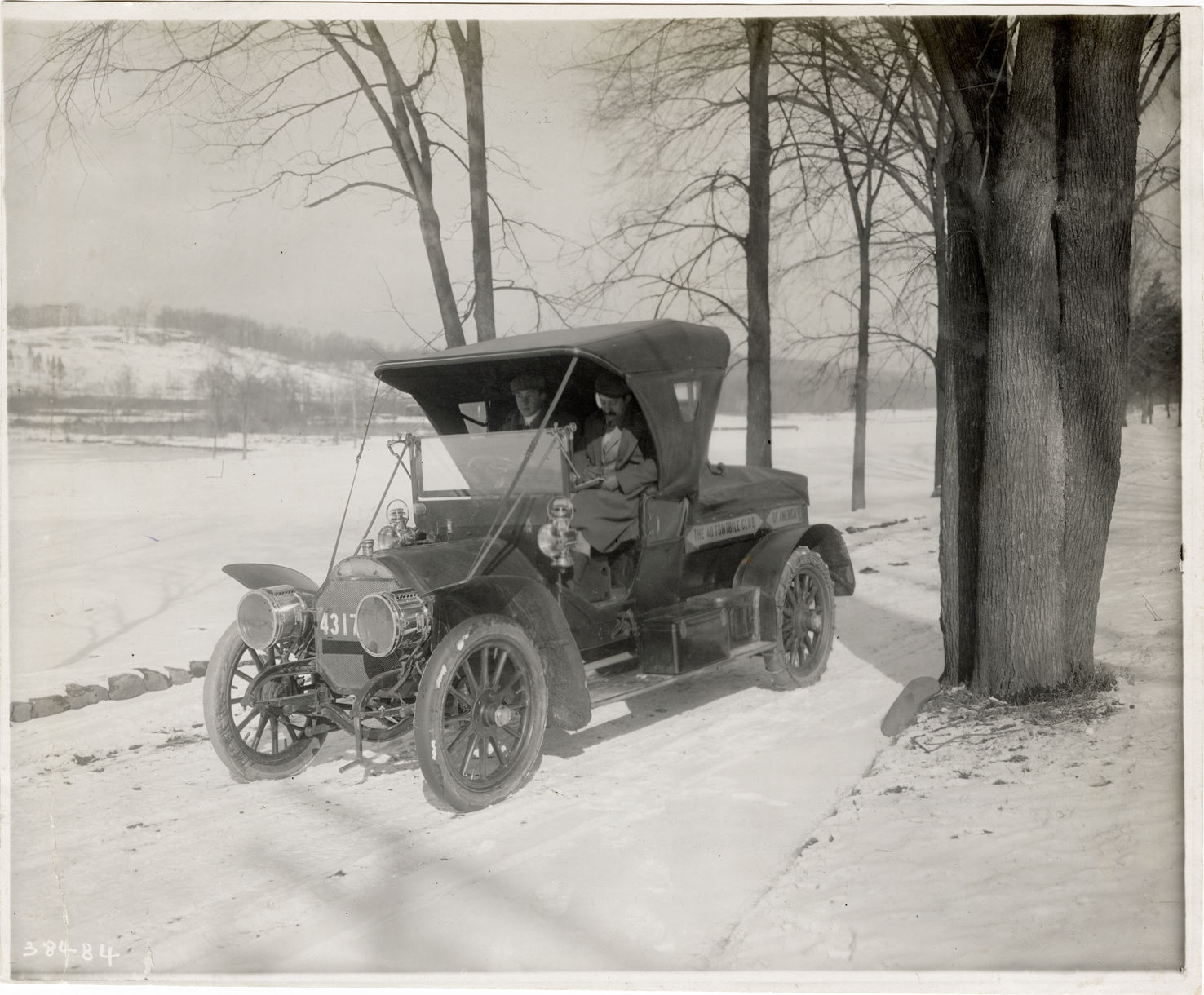 Motorists posing in 1907 Locomobile automobile during winter