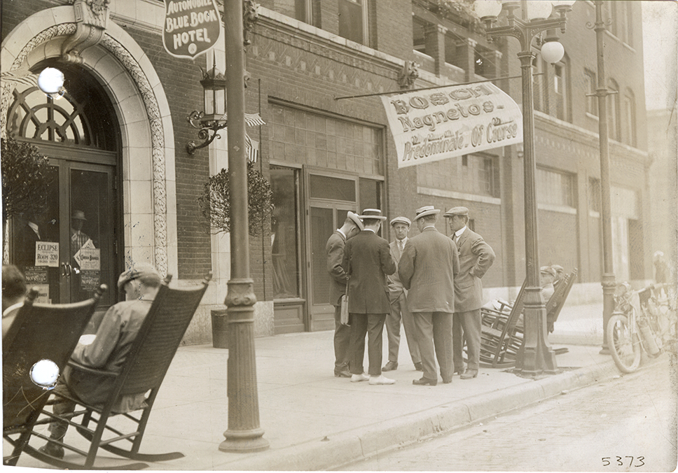 Men conversing in front of hotel, 1912 Federation of American Motorcyclists meet
