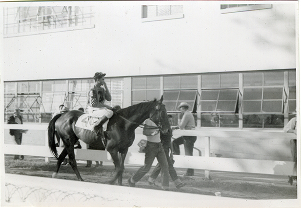 Jockey riding horse near stable, Michigan Racing Association racetrack