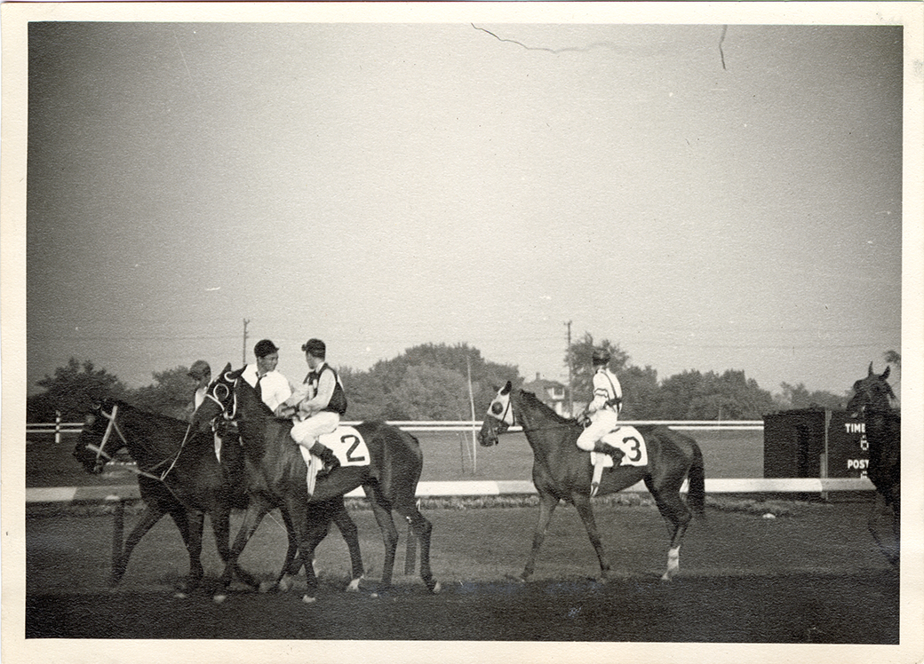 Outrider Louie Monti walking horse "Brownie" in front of grandstand, Hazel Park Raceway