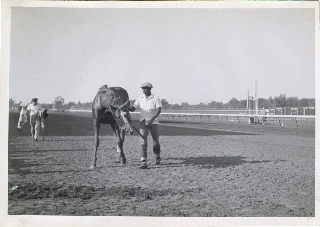 Groom leading horse on track, Michigan Racing Association racetrack