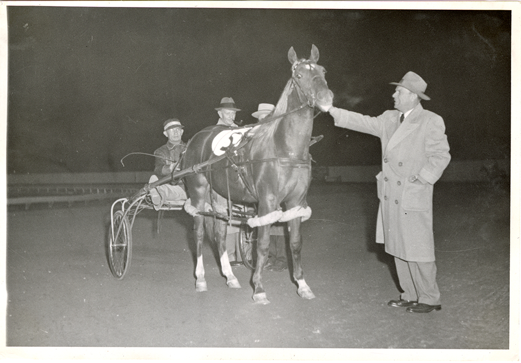Man posing with driver and harness racehorse, Michigan Racing Association racetrack
